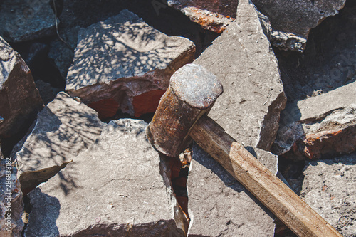 Photography Rusty sledgehammer on broken bricks and concrete stones.
