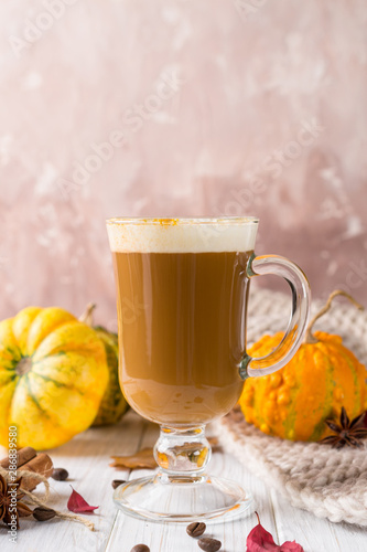 Cup of pumpkin spice latte with whipped cream on top and seasonal autumn spices, and fall decor. Traditional coffee drink for autumn or winter holidays, copy space.