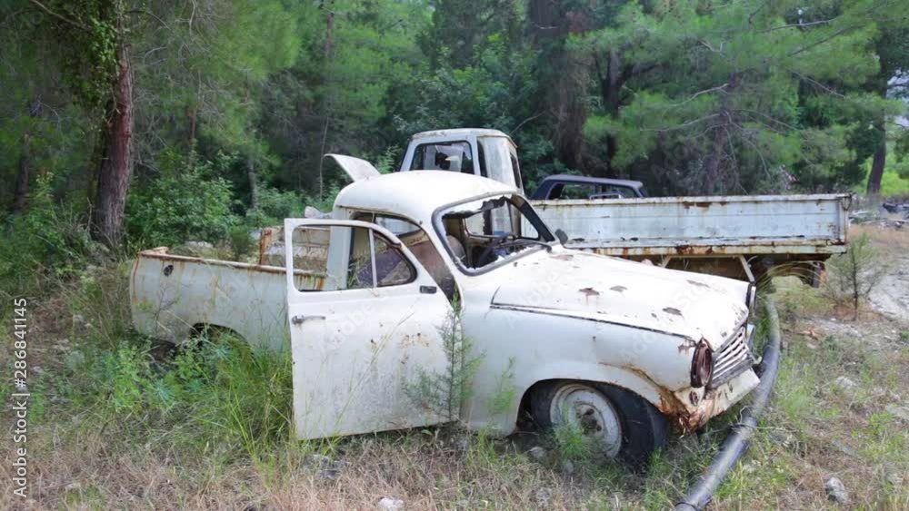 Closeup view of old rusty abandoned cars with peeling paint standing in wood outdoors. Real time full hd video footage. Closeup view of old rusty abandoned cars with peeling paint standing in wood outdoors. Real time full hd video footage.