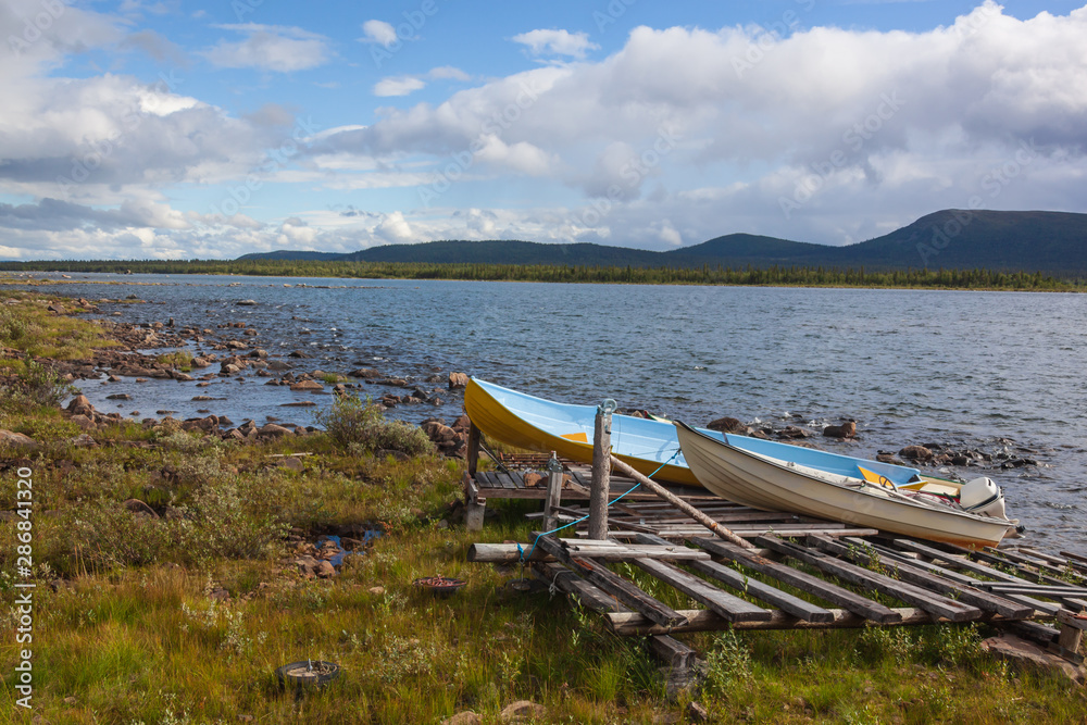 Colorful boats on the bank of the picturesque lake in Swedish Lapland, Norrbotten County
