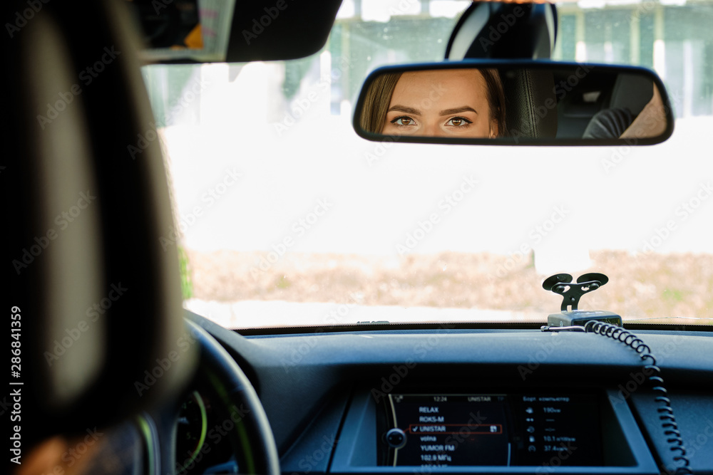 Reflection of female eyes in rearview mirror of a car