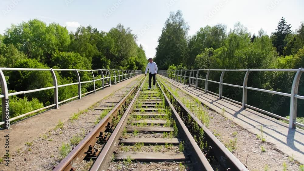 A man going along on an abandoned railway bridge from afar. Full shot. A man going along on an abandoned railway bridge from afar. Full shot.