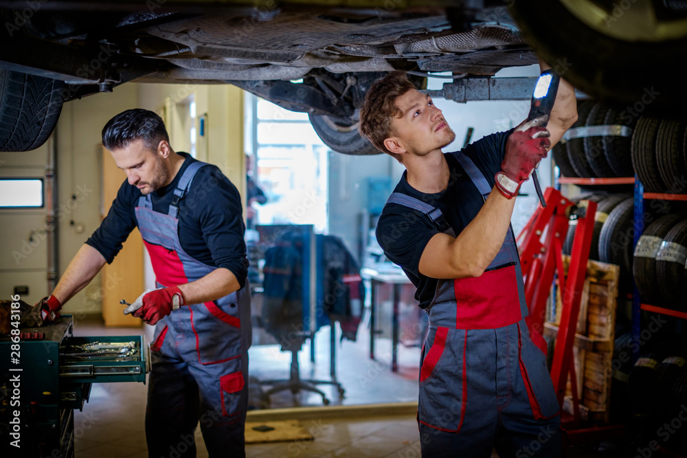 Car mechanic inspects suspension in a workshop