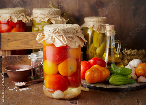 Obraz na płótnie Homemade pickled tomato and cucumber in glass jars on an wooden rustic background w salonie