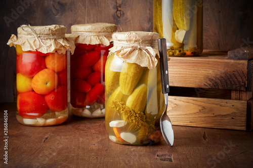 Obraz na płótnie Homemade pickled tomato and cucumber in glass jars in wooden rustic box w salonie