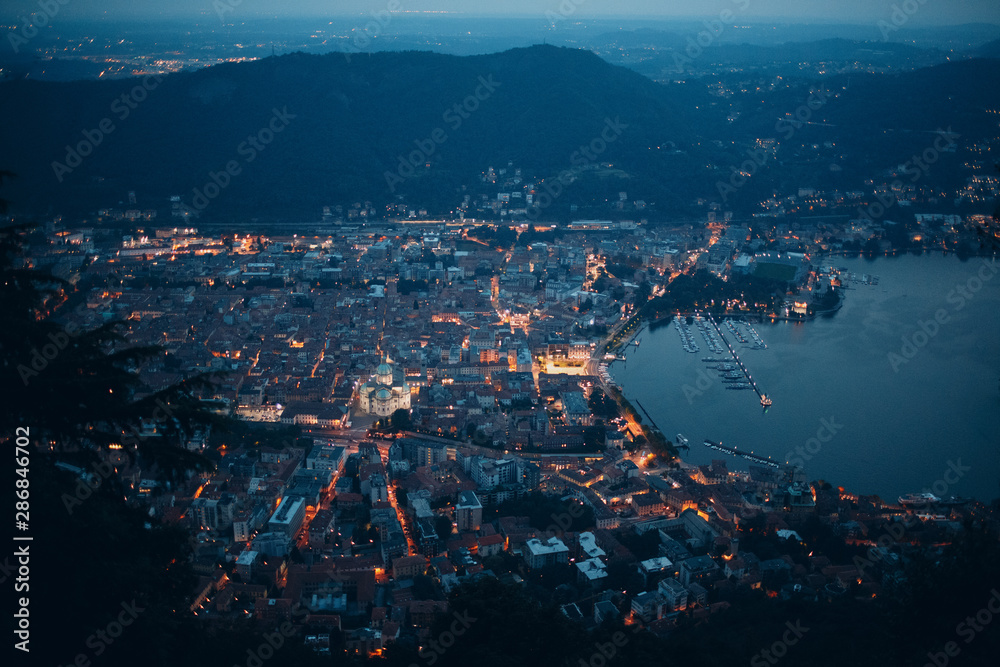 Top view of the night city of Como, Italy. Mountains, port and bay.