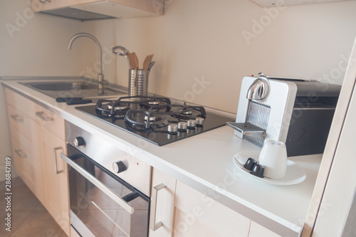 Modern kitchen. Countertop with assorted utensils, a sink, an oven, gas stoves and coffee maker