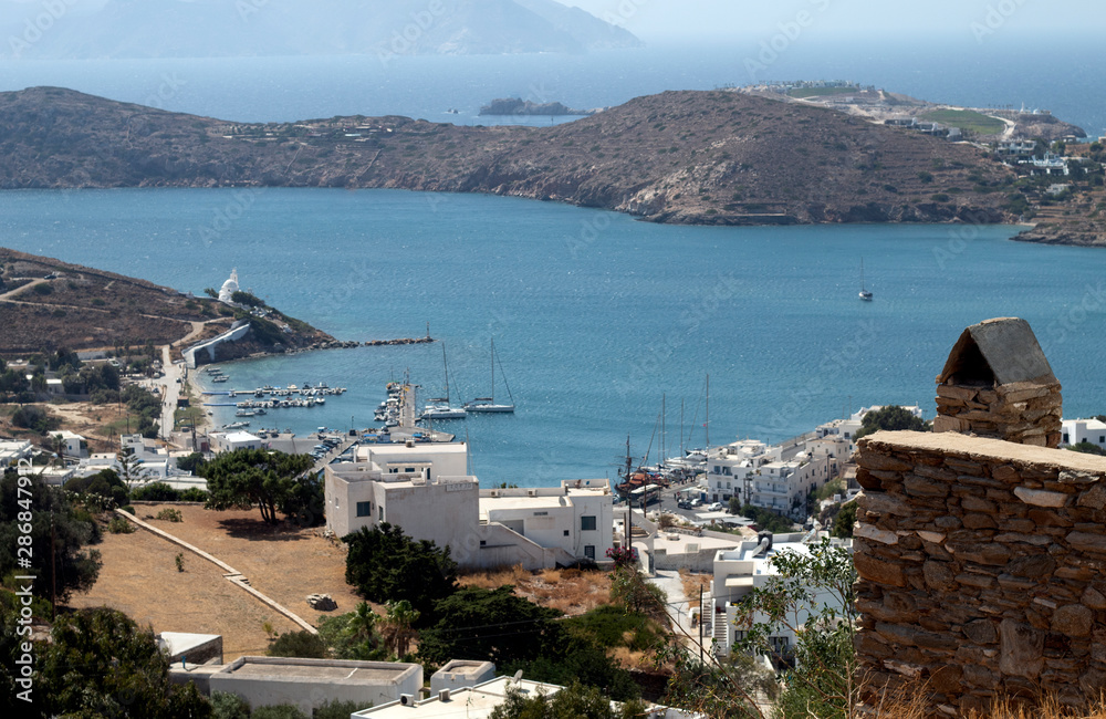 Greece, the island of Ios in the Cyclades. A view to sea and the port. Pleasure craft are moored. In the far distance is the neighbouring island of Sikinos.
