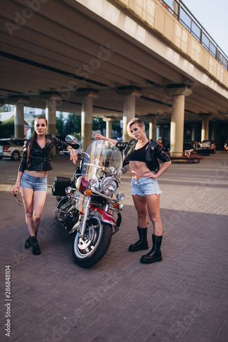 Sexy gorgeous young women outdoors with motorcycle on road. Friendship, beauty, sexy lady, transportation concept