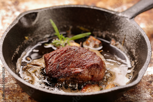 steak is fried in a pan with garlic and herbs