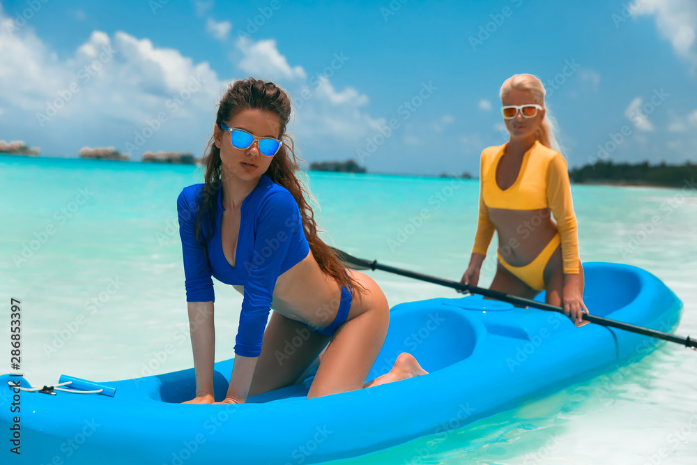 Two sexy bikini models in swimwear posing on kayak, on tropical beach  paradise island. Maldives paradise. Summer water sport, adventure outdoors.  Joyful young women kayaking together. Stock Photo | Adobe Stock