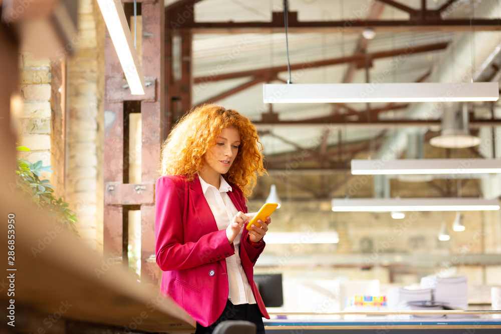 Office worker standing near window and using phone Office worker standing near window and using phone
