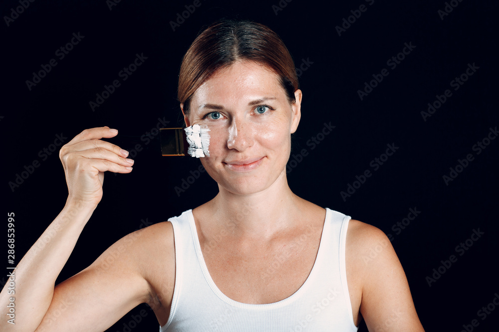Young woman applying make-up, paints face with painting brush and makeup. How not to do make up concept. Young woman applying make-up, paints face with painting brush and makeup. How not to do make up concept.