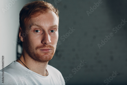 Portrait of a young blond man. He is wearing a white T-shirt. He is tired and thoughtful. © primipil