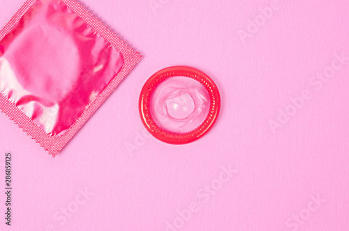Pink opened condom and condom in pack.