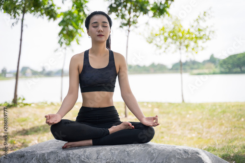 Young beautiful woman practices yoga and meditates outdoor at the mountain. Female doing yoga and meditate to relax and release stress.