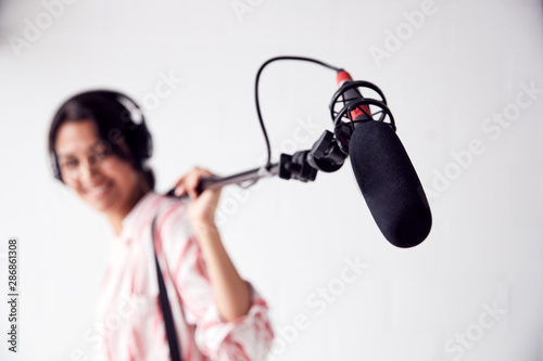 Portrait Of Female Sound Recordist Holding Microphone On Video Film Production In White Studio photo