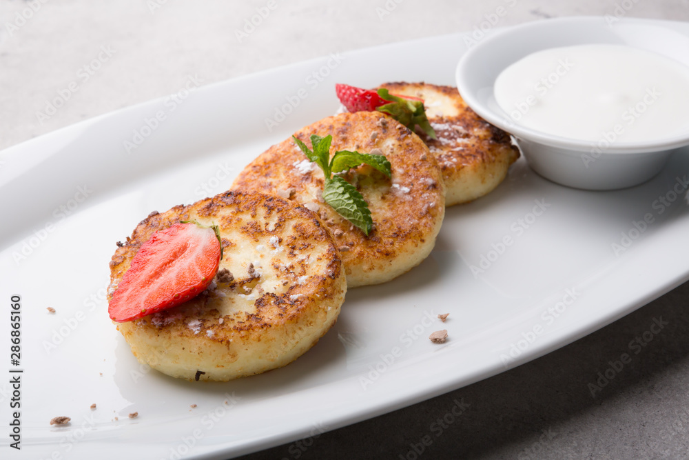 fried pancakes served with strawberry and sour cream