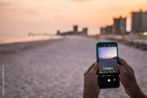 new cellular cell mobile phone at the beach taking a picture of the sunset