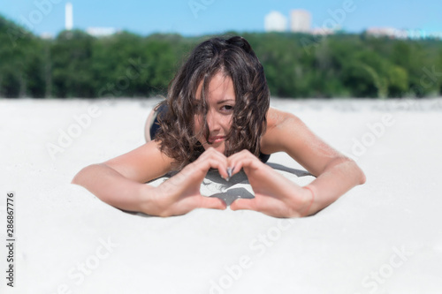 Beautiful brunette girl in a swimsuit, summer on a sandy beach, posing for the camera romantic mood, modern girl, stylish photo