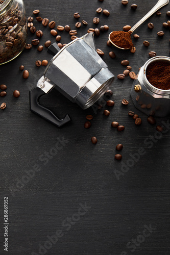 Separated parts of geyser coffee maker near glass jar and spoon on dark wooden surface with coffee beans