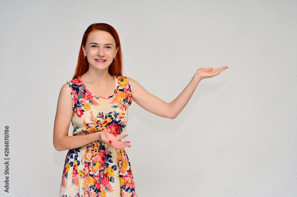 Portrait of a pretty red-haired girl, a happy young woman in a bright summer dress on a white background in the studio. Smiling, showing different emotions. Portrait of a pretty red-haired girl, a happy young woman in a bright summer dress on a white background in the studio. Smiling, showing different emotions.
