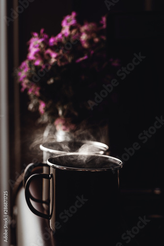 Kaffetassen mit frischem Kaffee vor einem Blumenstrauss photo