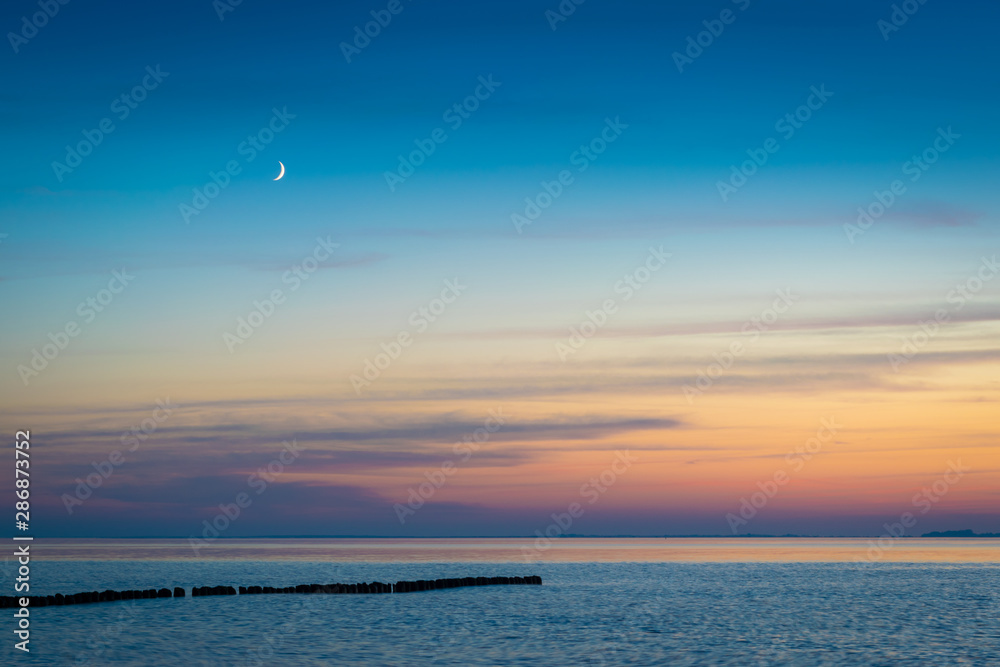 Mondsichel über Ostsee mit Buhne am Abend Mondsichel über Ostsee mit Buhne am Abend