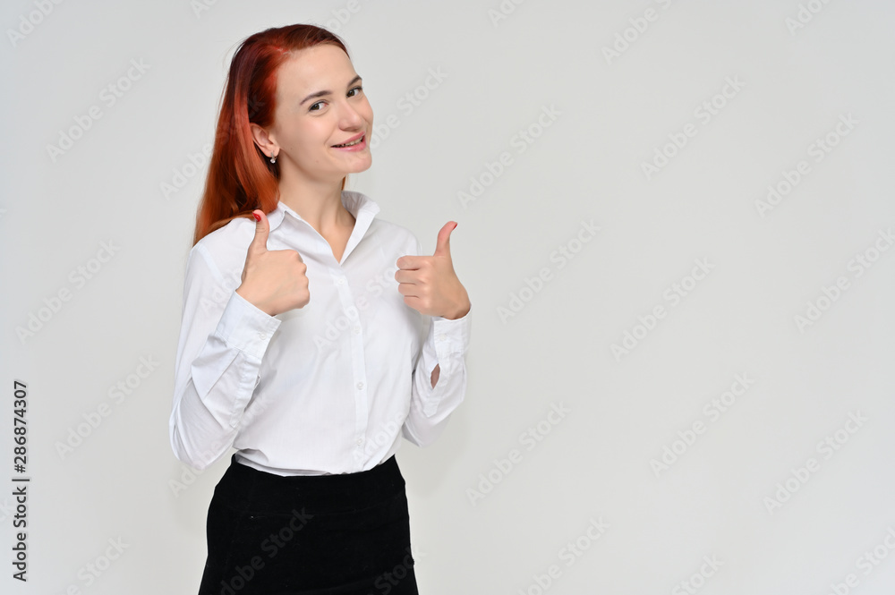 Portrait of a pretty red-haired girl, a happy young woman manager in a business suit on a white background in studio. Smiling, showing different emotions. Portrait of a pretty red-haired girl, a happy young woman manager in a business suit on a white background in studio. Smiling, showing different emotions.
