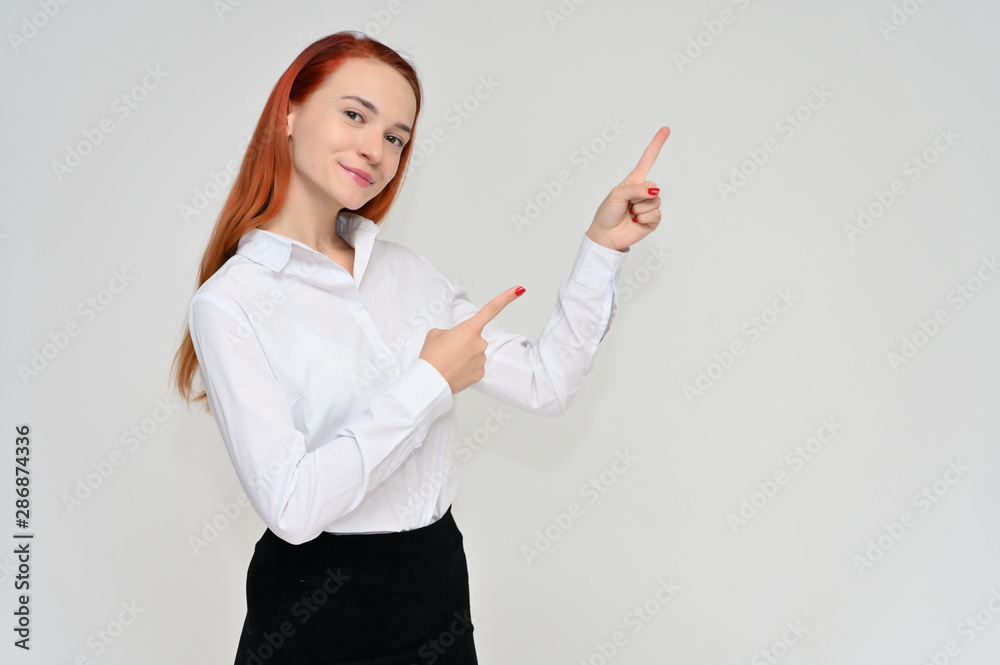 Portrait of a pretty red-haired girl, a happy young woman manager in a business suit on a white background in studio. Smiling, showing different emotions. Portrait of a pretty red-haired girl, a happy young woman manager in a business suit on a white background in studio. Smiling, showing different emotions.