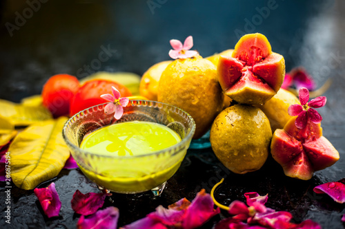 Best cheap face mask for tanned skin on wooden surface un a glass bowl consisting of guava leaves paste well mixed with some tomato pulp. Shot with entire ingredients with fantastic colors. photo