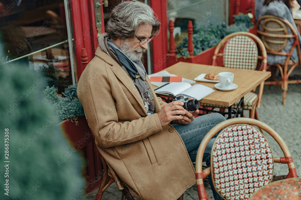 Elegant senior man holding retro camera at outdoor cafe Elegant senior man holding retro camera at outdoor cafe