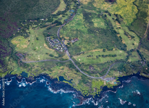 Aerial view of a small cluster of houses at Puuo point near Kuhua bay next to a rugged black lava rock coastline on the big island of Hawaii