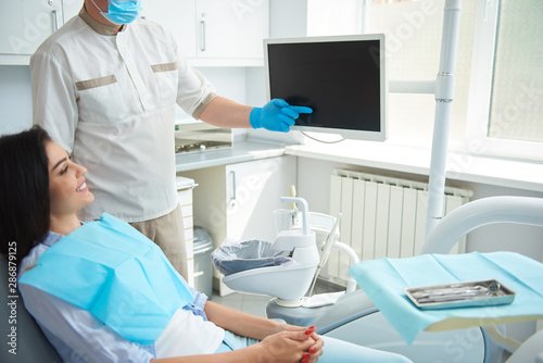 Male dentist in gloves holding hand near screen