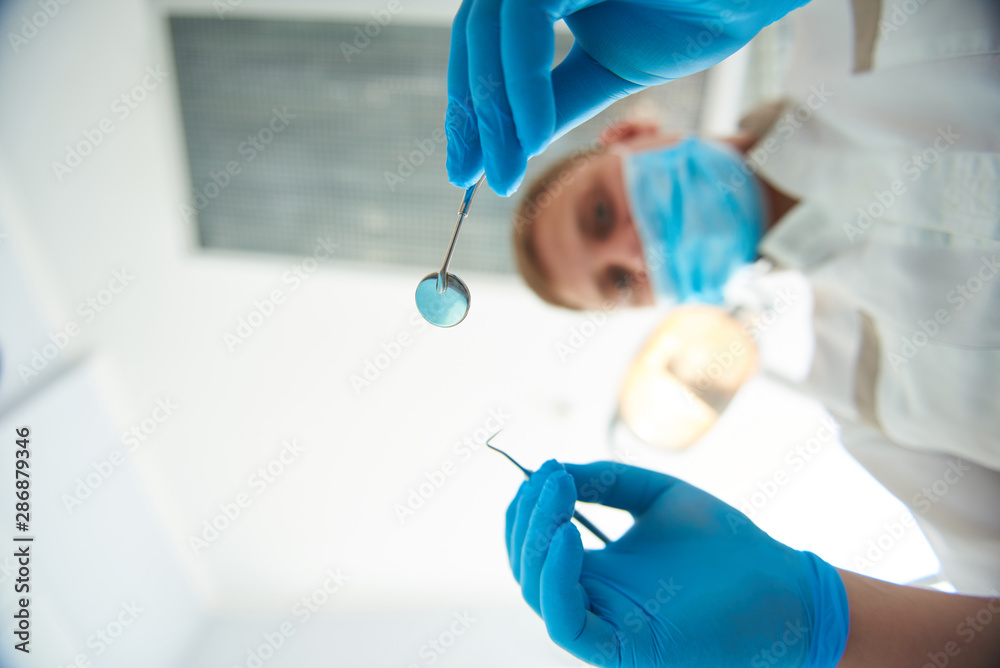 Fototapeta premium Professional adult stomatologist is holding dental tools