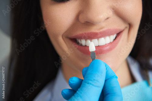 Doctor choosing teeth model for happy woman