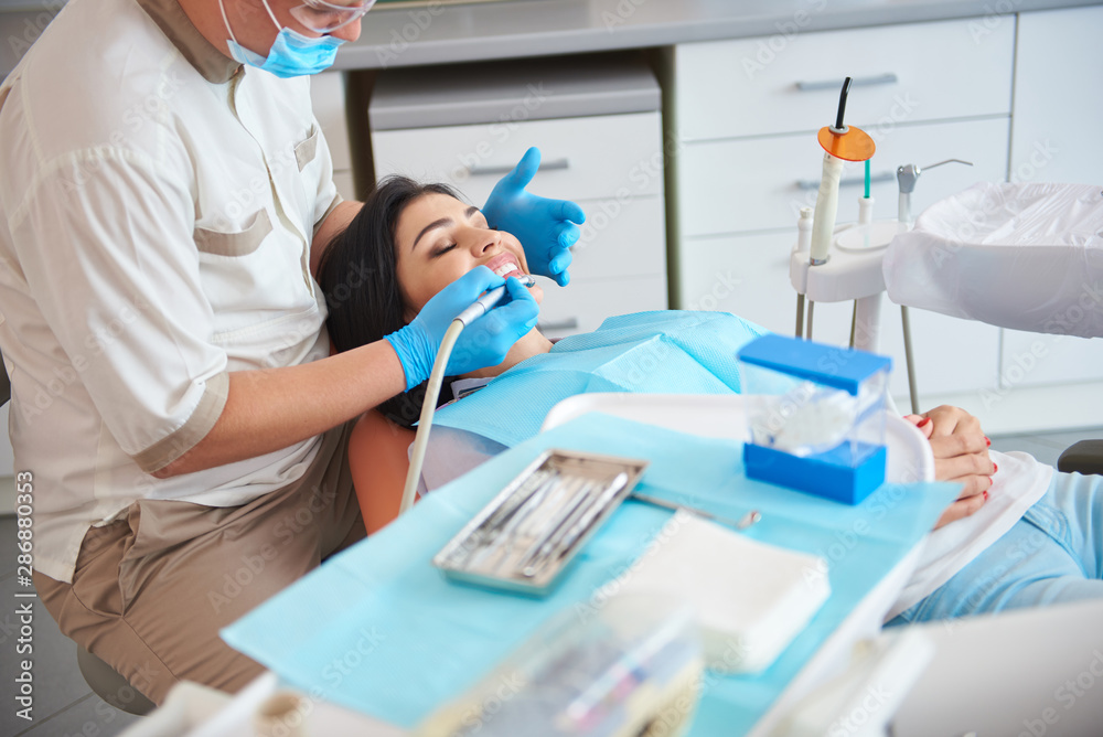 Fototapeta premium Dentist in protective mask is treating teeth