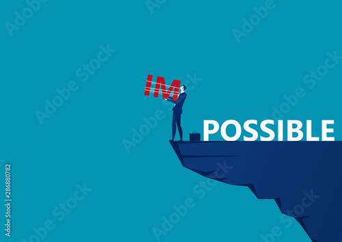 business man holding impossible text for abandoned IM word on top mountain, metaphor to success, challenge, motivation,achievement,concept
