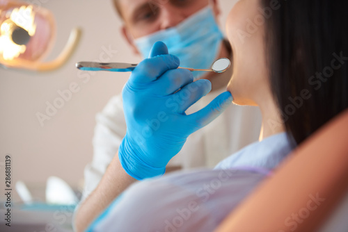 Professional male stomatologist is holding dental mirror