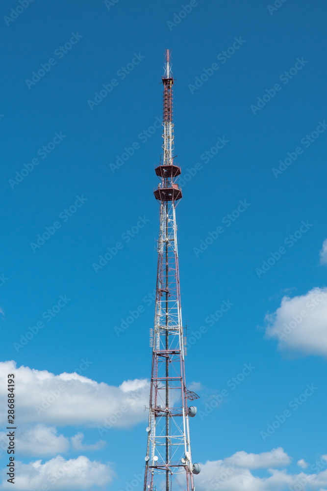 telecommunication tower with antennas on the background of the sky with clouds