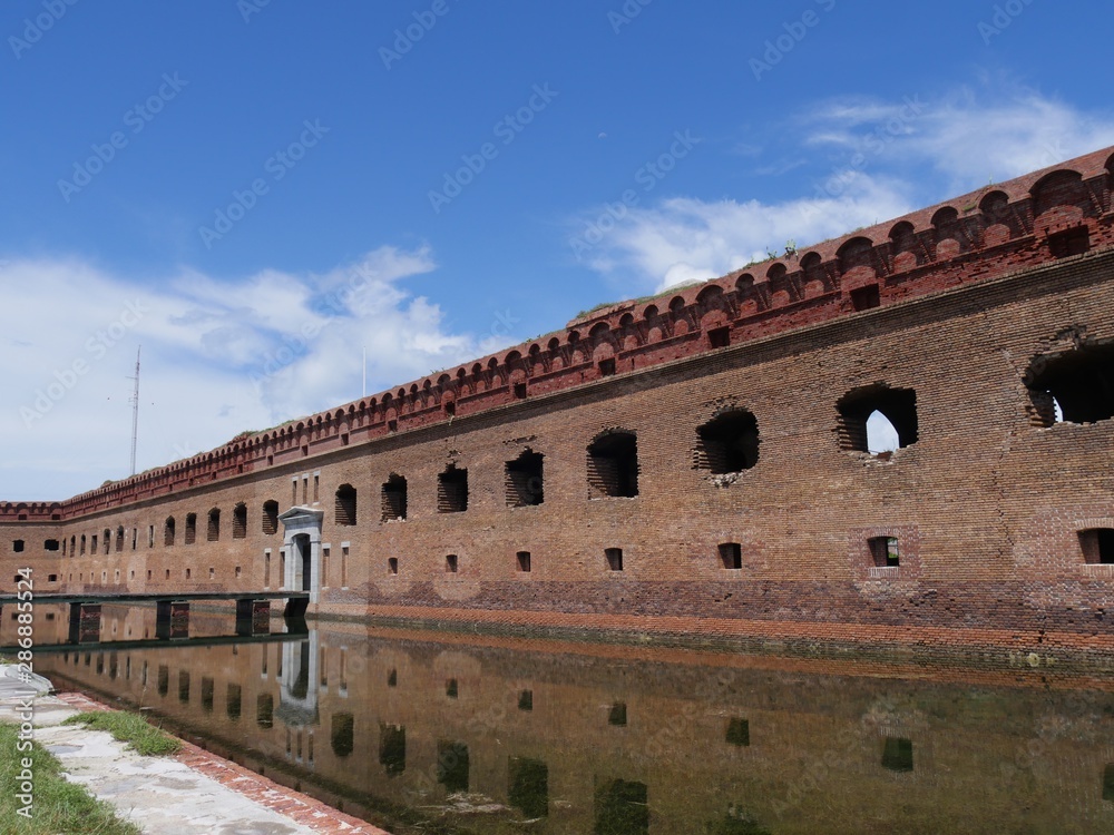 Side view of the entrance to Fort Jefferson, Dry Tortugas National Park in Florida, with the fort reflected in the moat waters.
