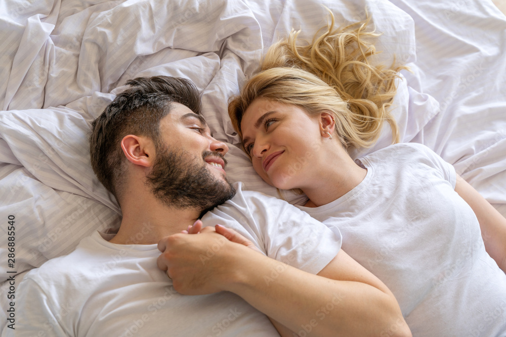 Smiling couple lying down together in bedroom Smiling couple lying down together in bedroom