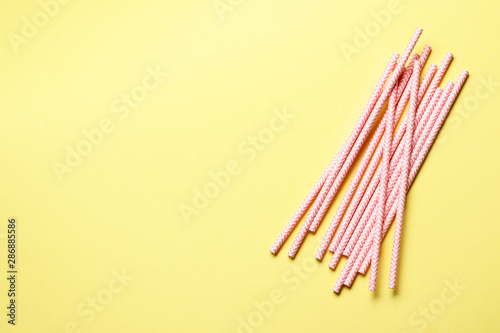Pink paper straws. Pink tubules for cocktails on a yellow background with place for text