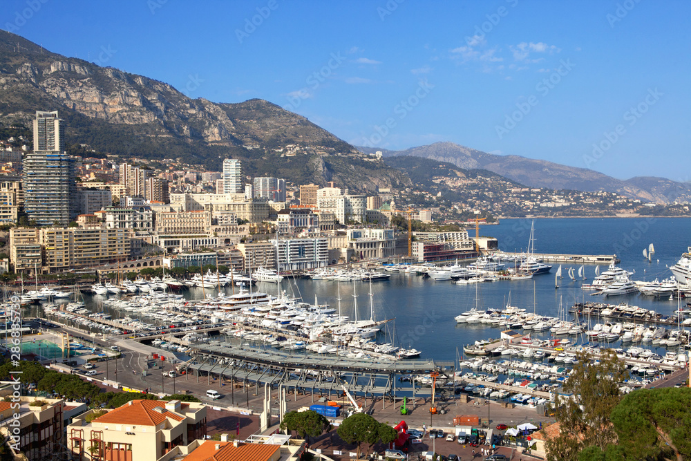 Ships in the bay of Monaco on a blue background. City houses background.