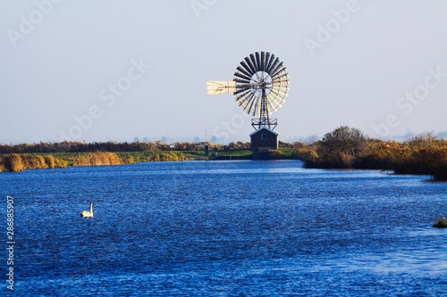 Ancient wind turbine in dutch rural landscape with river near traditional village Zaanse Schans, Netherlands