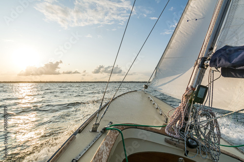 Sailing boat sailing fast into the sunset on choppy sea