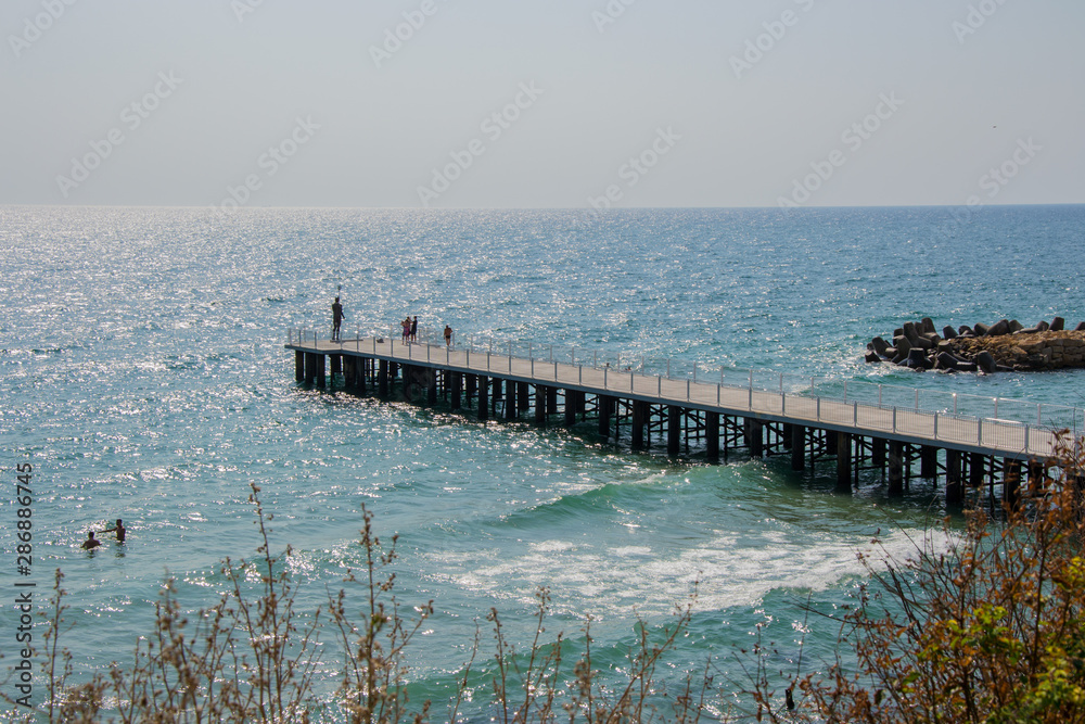 People on a pier with statue of Poseidon, blue sea and sky, holiday destination - St Constantine and Elena, Varna, Bulgaria