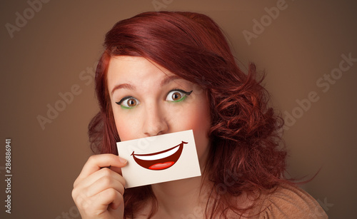 Photo Person holding card in front of his mouth with ironic smile