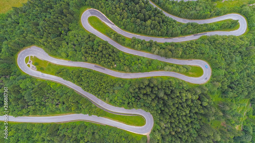 AERIAL: Cars driving along scenic mountain highway with sharp hairpin turns photo