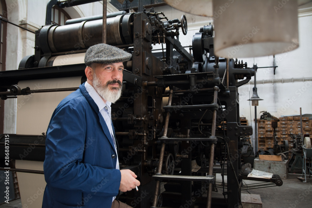 Man with beard working on printing press Man with beard working on printing press